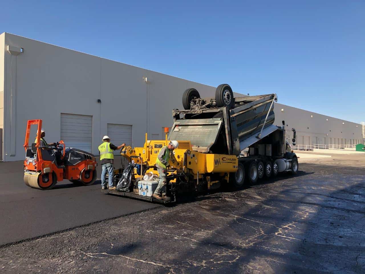 Two workers from JD Asphalt Inc. resurfacing a driveway